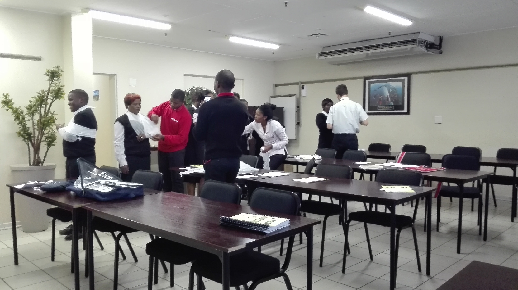 Participants practicing bandaging techniques in a classroom setting during a first aid training session.