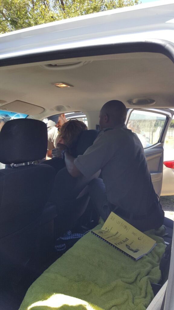 Participants practicing vehicle extraction techniques, assisting an injured person in a car during a training session