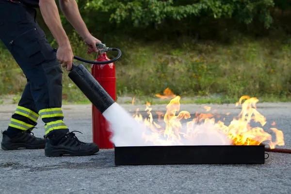 Person using a CO2 fire extinguisher to put out a Class B fire during a training session
